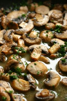 mushrooms are being cooked in a pan with parsley on the top and green garnish