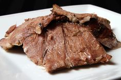 a white plate topped with meat on top of a table