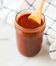 a wooden spoon sticking out of a jar filled with ketchup on top of a table