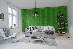 a living room filled with furniture and a soccer field wall mural on the wall behind it