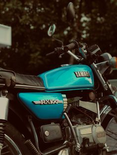 a blue yamaha motorcycle parked next to a tree