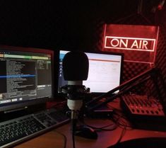 a desk with two computer monitors and a microphone in front of a red on air sign