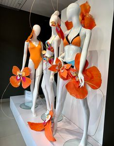 three mannequins dressed in orange swimsuits and flowers