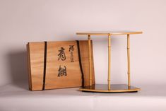 a wooden box with writing on it next to a small table that is shaped like a bamboo stand