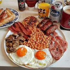 an english breakfast with eggs, bacon, beans and toast on a plate next to coffee