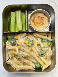 a metal tray filled with pasta and veggies next to dipping sauce on the side