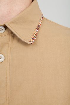 a man wearing a tan shirt with buttons on the collar