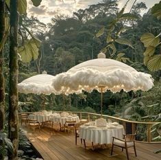 an outdoor dining area with tables, chairs and umbrellas covered in white linens