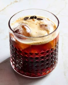 an iced drink in a glass with ice and raisins on the rim, sitting on a marble surface