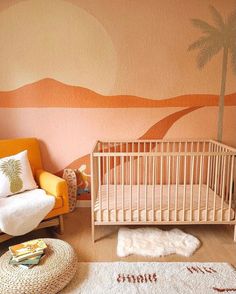 a baby's room with a palm tree painted on the wall and an orange chair