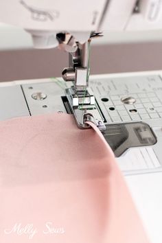 the sewing machine is working on the pink fabric that has been sewned into it