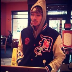 a young man wearing a hoodie using a laptop computer in a restaurant or bar