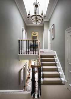 a staircase leading up to the second floor with chandelier hanging from the ceiling