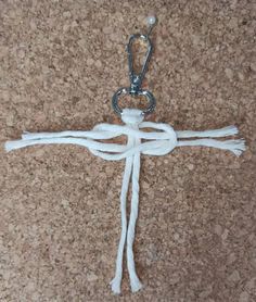 a crucifix made out of white yarn on a corkboard floor with a pair of scissors