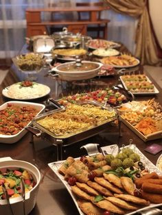 a buffet table filled with lots of different types of food on plates and serving trays