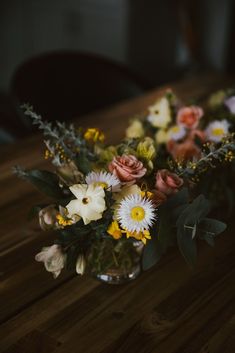 a vase filled with lots of flowers on top of a wooden table