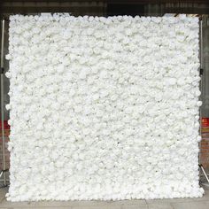 a large white flower covered wall in front of a brick building