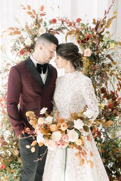 a bride and groom standing next to each other in front of a floral arch at their wedding