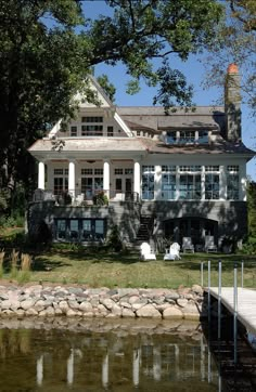 a large white house sitting on top of a lush green field next to a lake