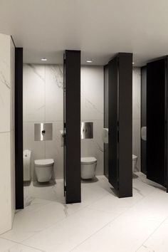 an empty bathroom with three stalls and two toilets in the corner, all black and white