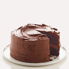 a chocolate cake on a white plate with one slice missing