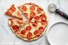 a pepperoni pizza cut into four slices on a marble counter top next to a spatula