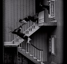 two men doing tricks on their skateboards in front of a stair case with railings