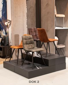 three different colored chairs on display in a room