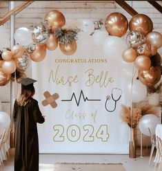 a graduate standing in front of a backdrop with balloons