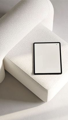 an empty square plate sitting on top of a white cushioned pillow with a black border