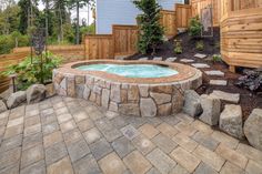 an outdoor hot tub surrounded by rocks and landscaping