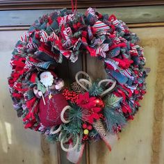 a christmas wreath hanging on the front door with ornaments around it and an ornament