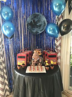 a birthday party with balloons, cake and firetrucks on a black table