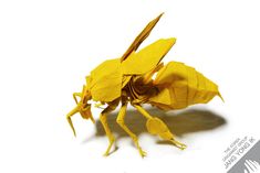 a yellow origami insect sitting on top of a white surface