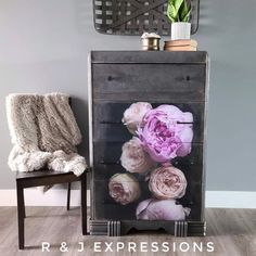 a black cabinet with flowers on it next to a chair