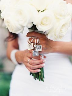 a bride holding a bouquet of white roses and two wedding rings on her finger,