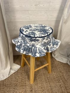 a blue and white hat sitting on top of a stool in front of a curtain