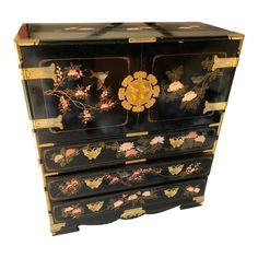 an antique black and gold painted dresser with flowers on the front, two doors open