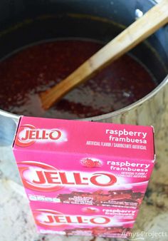 a box of jello sitting in a pot with a wooden spoon next to it