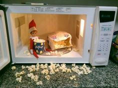 an elf is sitting in the microwave with popcorn