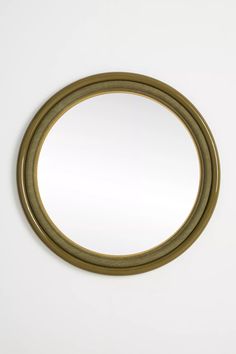 a round mirror is shown against a white wall