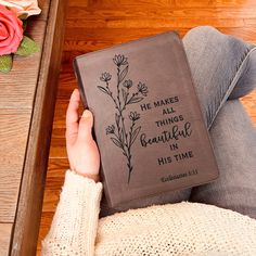 a person sitting on the floor with a book in their lap and flowers behind them