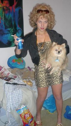 a woman in leopard print dress holding a small dog and drinking from a soda cup