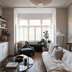 a living room filled with furniture and a large window covered in shuttered glass shades