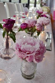 several vases filled with flowers sitting on top of a white tablecloth covered table