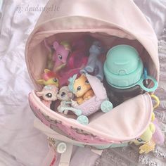 a pink bag filled with littlest pet toys on top of a white bed covered in lace