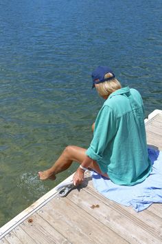 a person sitting on a dock near the water