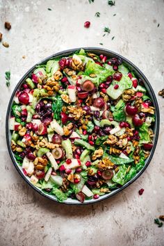 a salad with apples, cranberries and walnuts in a bowl on a table