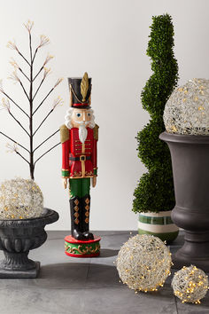 a nutcracker is standing next to some potted plants and balls on the ground