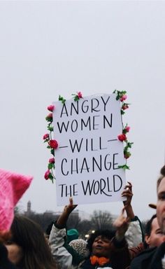 a group of people holding up signs in the air with one person wearing a pink hat